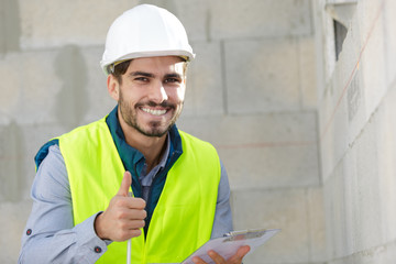 young smiley engineer holds clipboard thumbs up