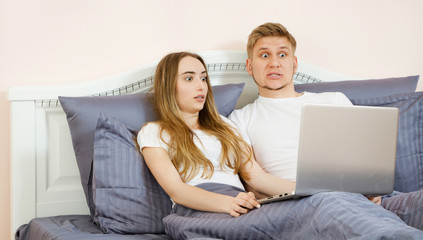 Closeup Surprised emotional white Lover or couple when using technology laptop on the bed in bed room at modern home, couple watching something emotional on laptop in the bed