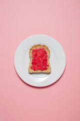 Tostada de corazones dentro de un plato blanco sobre fondo rosa