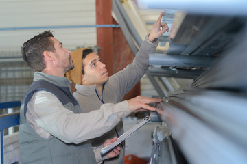 workers with clipboard checking stock of pvc pipes