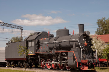 Black steam locomotive on a sunny day at the station.