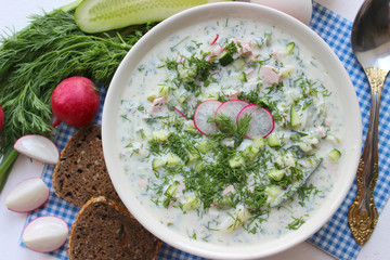 Okroshka is a traditional Russian summer cold soup in a ceramic bowl. Ingredients potatoes,...