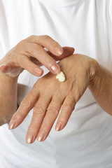 Older woman applying cream on hands close-up isolated on white background