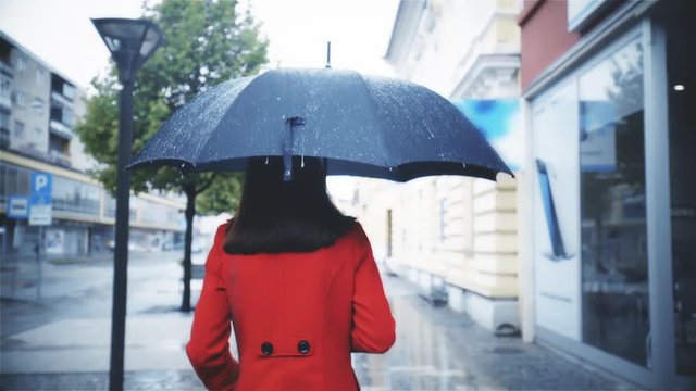 Woman in red walk under black umbrella