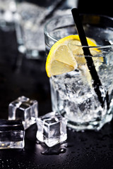 Glasses with fresh cold carbonated water with lemon slices and ice cubes closeup.