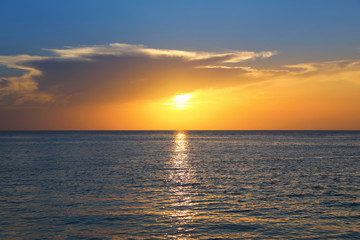 Colorful empty seascape with shiny sea over cloudy sky and sun during sunset in Cozumel, Mexico