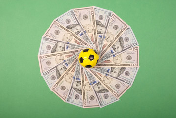 Football little ball lying on  mandala kaleidoscope from money. Money and soccer ball - sport and...