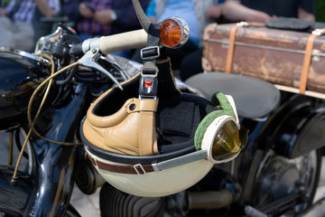 vintage crash helmet is hanging on the handlebar of a classic oldtimer motorbike