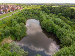 Small lake over looking a suburban housing estate in the UK, taken on a part cloudy sunny day 