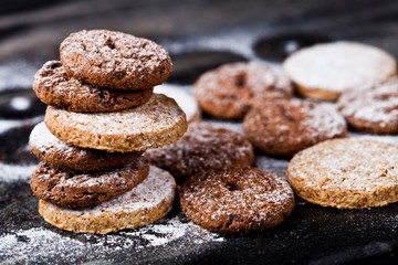 Chocolate chip and oat fresh cookies with sugar powder stack.