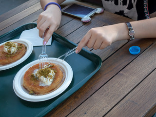 Young Women Eat Turkish Sweet Kunefe with Pistachio