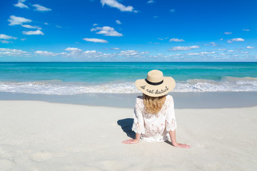 Woman sits on ocean beach in Cuba, wearing hat, beautiful sky and water, Do not disturb, perfect background, free space