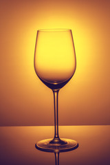 an elegant empty glass of wine  is standing opposite the light