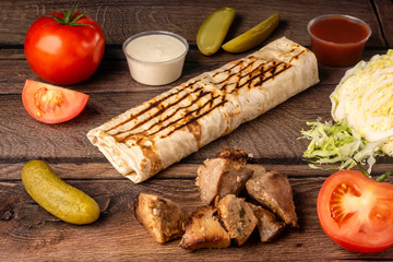 Takeaway fast food in pita bread with fresh vegetables, pork and sauce
