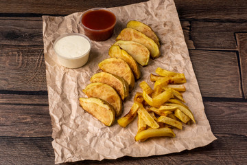 Rustic potatoes and french fries with sauces on rough paper