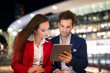 People using tablet at night in a city