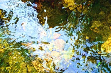 eflections and ripples on the surface of the current of the river, with visible rocks under the water