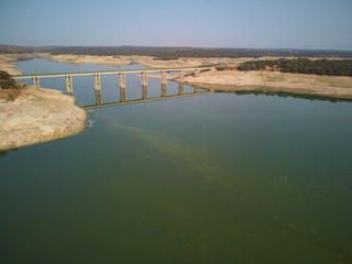 Aerial view of the Valdecañas reservoir, with green water from the algae and natural lines of the descent of the water. Natural texture