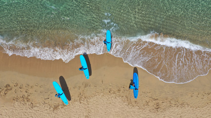 Fototapeta na wymiar Aerial drone top view photo of young team of surfers enjoying tropical wavy turquoise sea sandy beach in exotic caribbean island