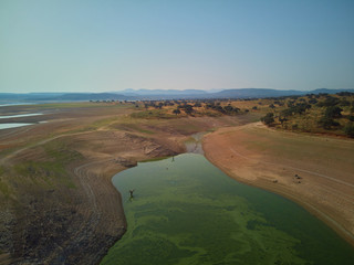 Aerial view of the Valdecañas reservoir, with green water from the algae and natural lines of the...