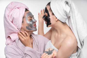 the girl puts her sister a cosmetic mask on her face. They have fun and indulge in the process....