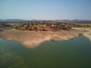 Aerial view of the Valdecañas reservoir, with green water from the algae and natural lines of the...