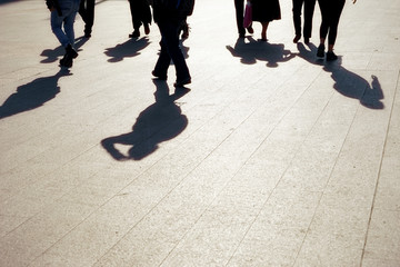 Close up image of silhouetted crowd of people walking on city street