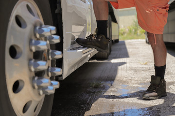 Close-up of trucker legs in boots and shorts, climbing stairs in a truck