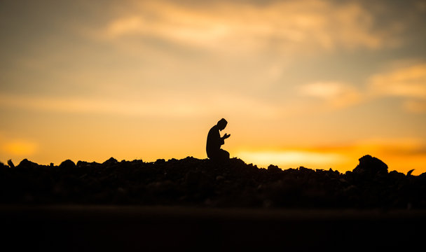 Concept Of Religion Islam. Silhouette Of Man Praying On The Background Of A Mosque At Sunset