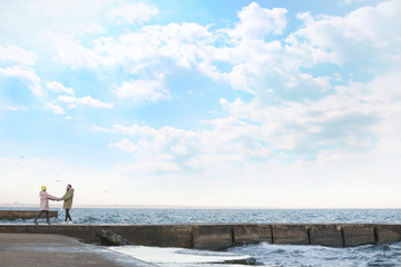 Lovely young couple walking on pier near sea