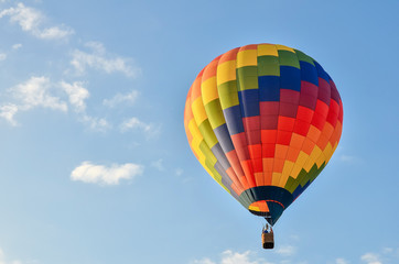 Colorful hot air balloon heading up in blue sky. Copy space.