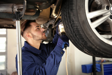 Technician checking modern car at automobile repair shop