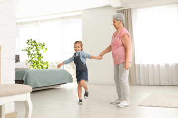 Obraz premium Cute girl and her grandmother dancing at home