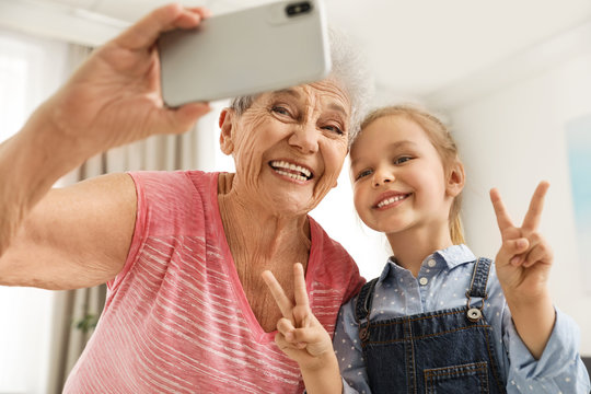 Cute girl and her grandmother taking selfie  at home