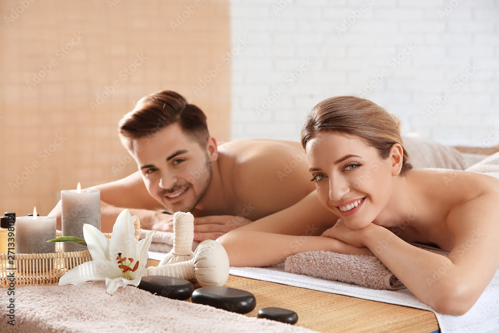 Poster Young couple with spa essentials in wellness center