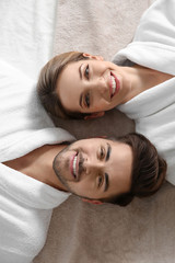 Happy young couple wearing bathrobes, top view. Visit to spa salon