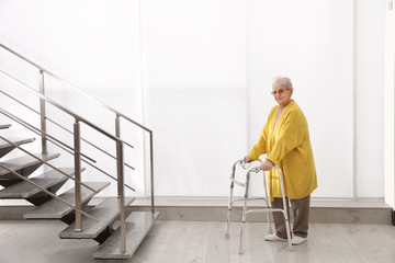 Senior woman with walker near stairs in hospital