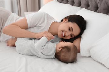 Portrait of mother with her cute baby lying on bed indoors