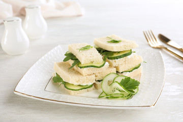 Plate with tasty cucumber sandwiches served on table