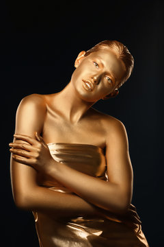 Portrait of beautiful lady with gold paint on skin against black background
