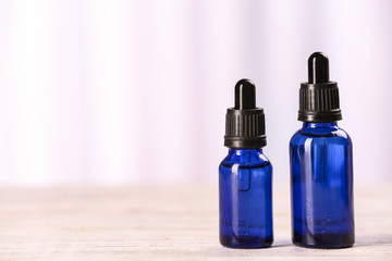 Bottles of essential oils on table against light background, space for text. Cosmetic products