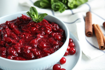 Bowl of tasty cranberry sauce with mint on table, closeup