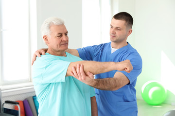 Obraz premium Professional physiotherapist working with senior patient in rehabilitation center