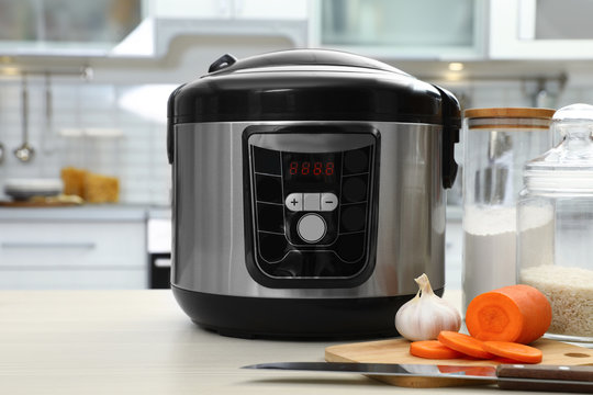 Modern multi cooker and products on table in kitchen