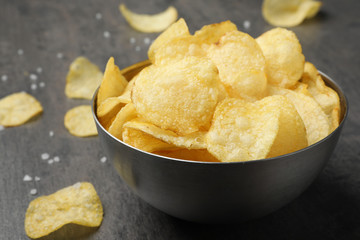 Delicious crispy potato chips in bowl on table, closeup