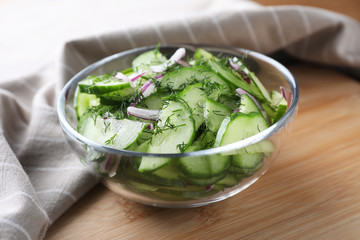 Bowl of tasty cucumber salad served on wooden table