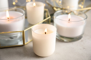 Fototapeta na wymiar Burning aromatic candles in holders on table