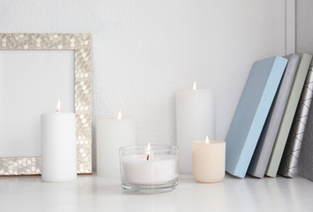 Fototapeta na wymiar Burning aromatic candles in holders on bookshelf