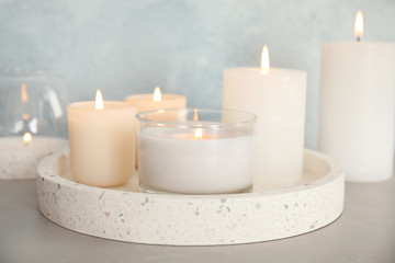 Tray with burning aromatic candles on table