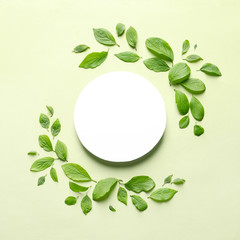 Flat lay composition with blank card and spring green leaves on color background. Space for text